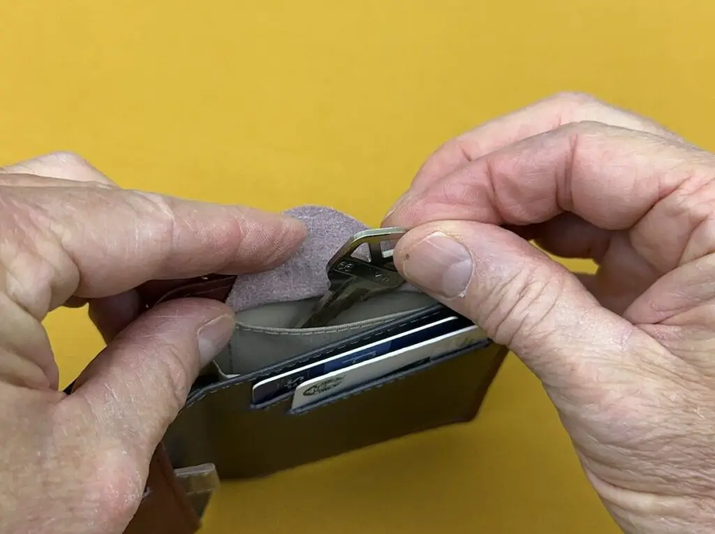 Bellroy Note Sleeve inserting key in coin pocket